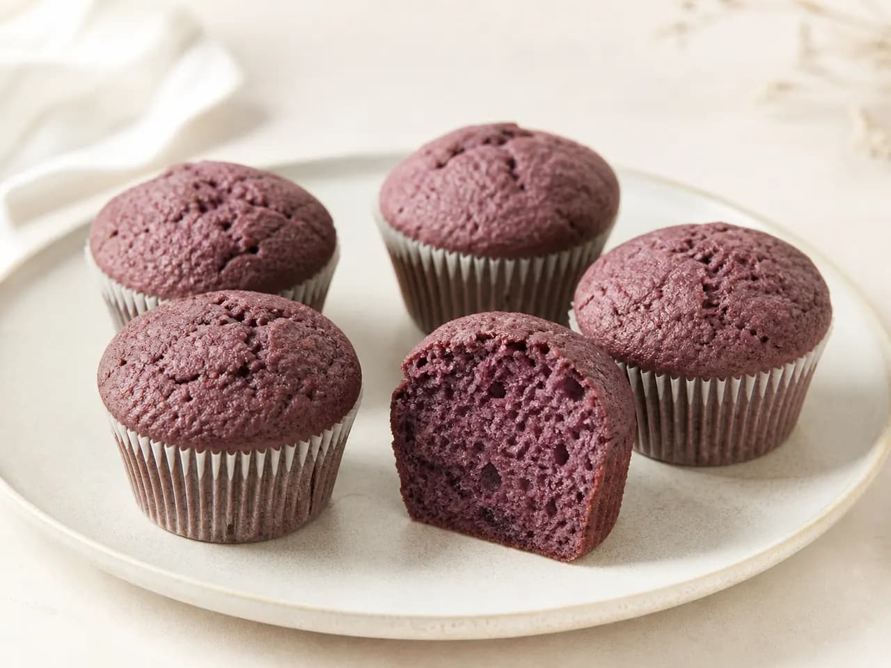 Finished purple açaí berry muffins with one muffin cut open